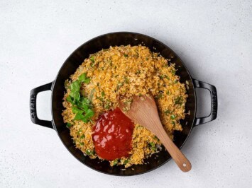 Adding tomato sauce to rice mixture