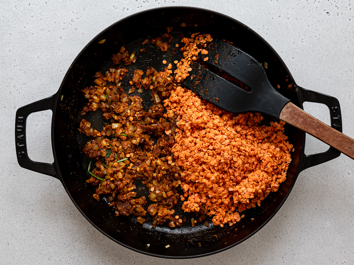 Adding lentils to onion mixture in pan.