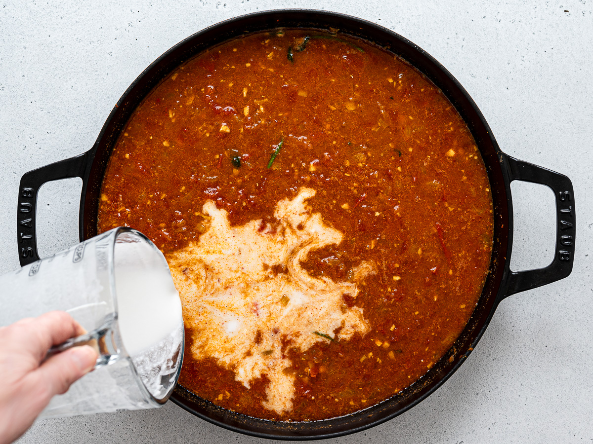 Pouring coconut milk into soup.