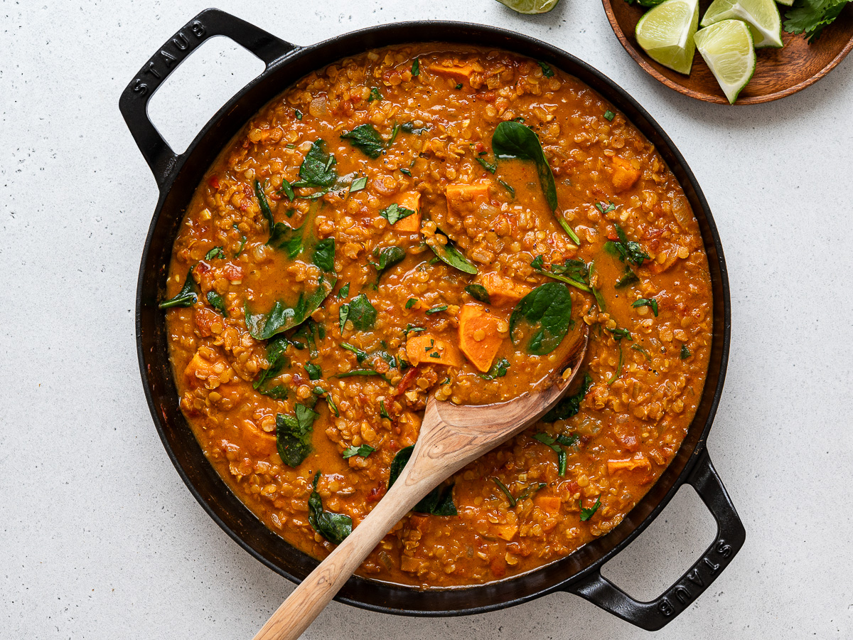 Finished soup in skillet with large wooden serving spoon.