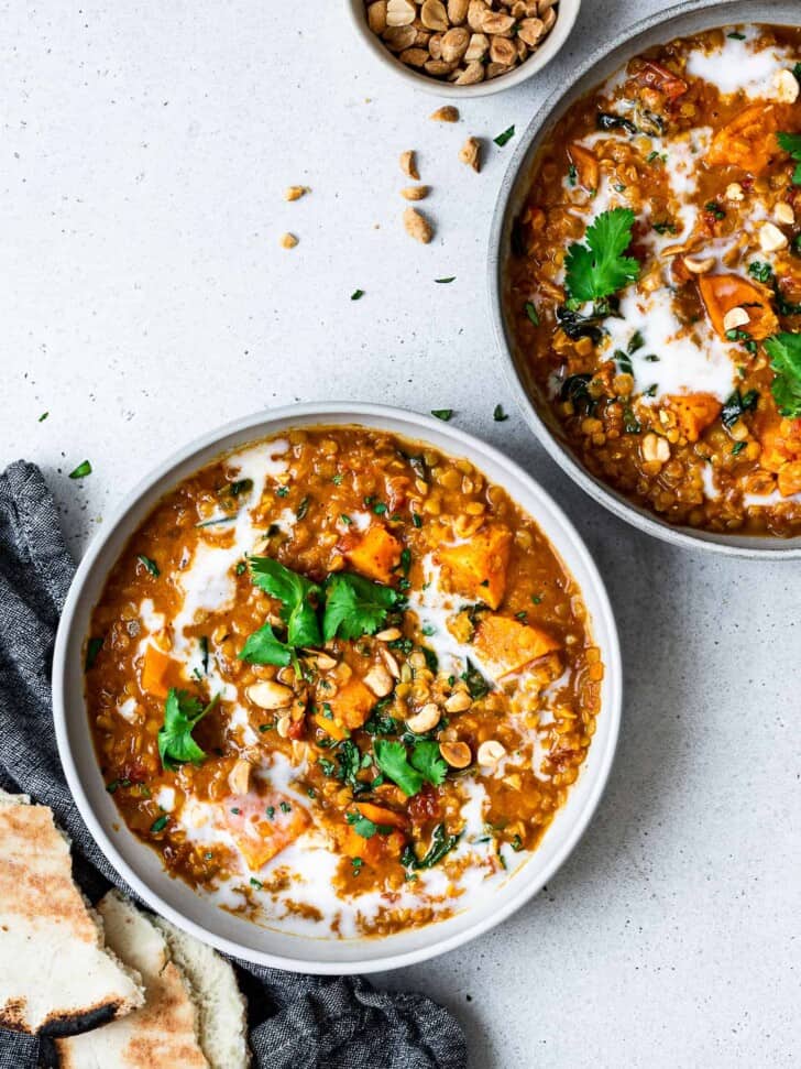 curried red lentil soup served in bowls with garnishes