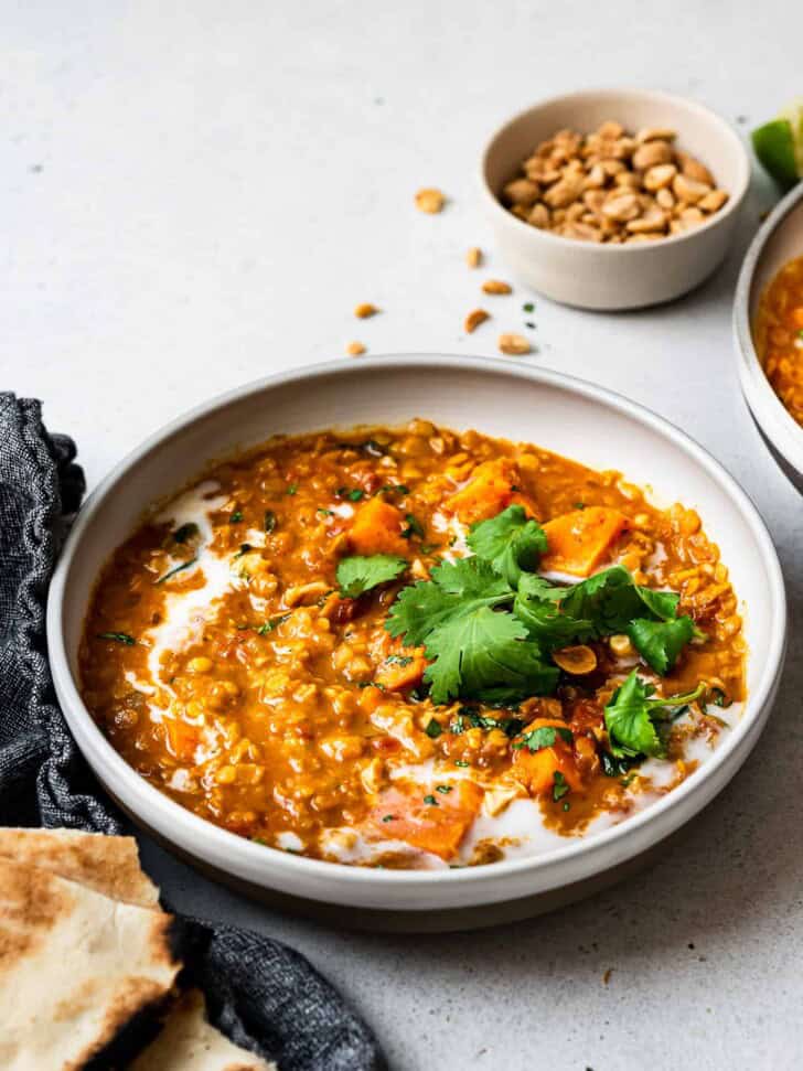 side view of curried red lentil soup served in bowls with garnishes