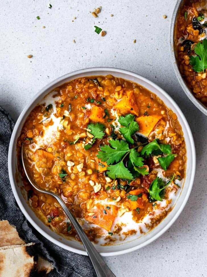 curried red lentil soup served in bowls with garnishes