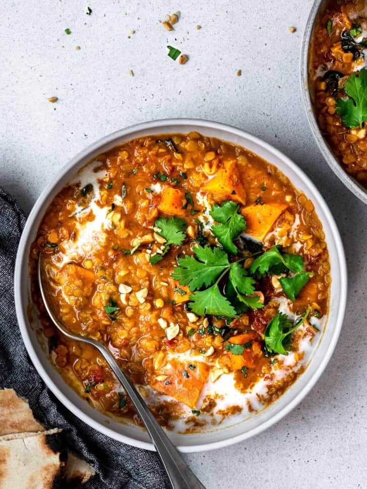 curried red lentil soup served in bowls with garnishes