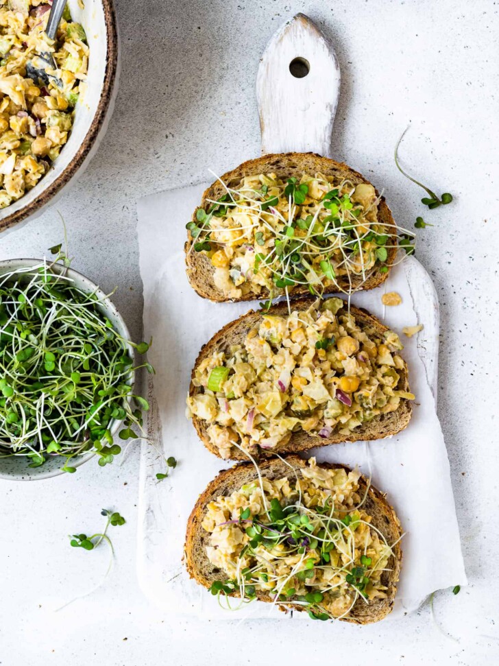 making chickpea salad sandwiches with sliced bread topped with micro greens