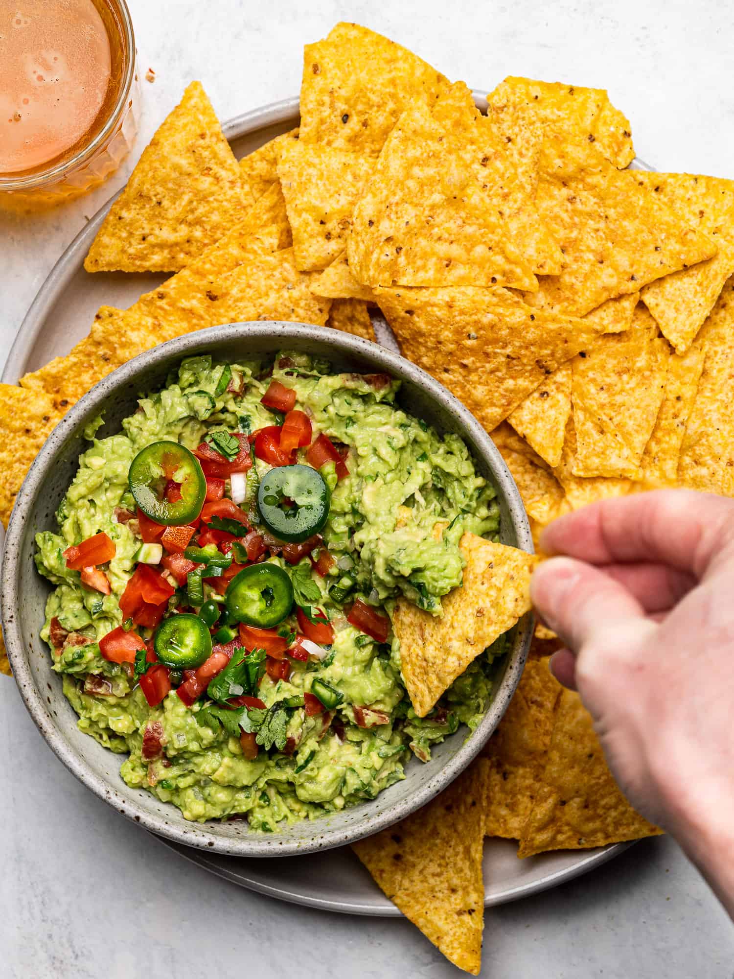 The best guacamole served in a bowl with a hand dipping a tortilla chip
