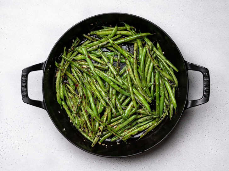 beans tossed with sauce in skillet