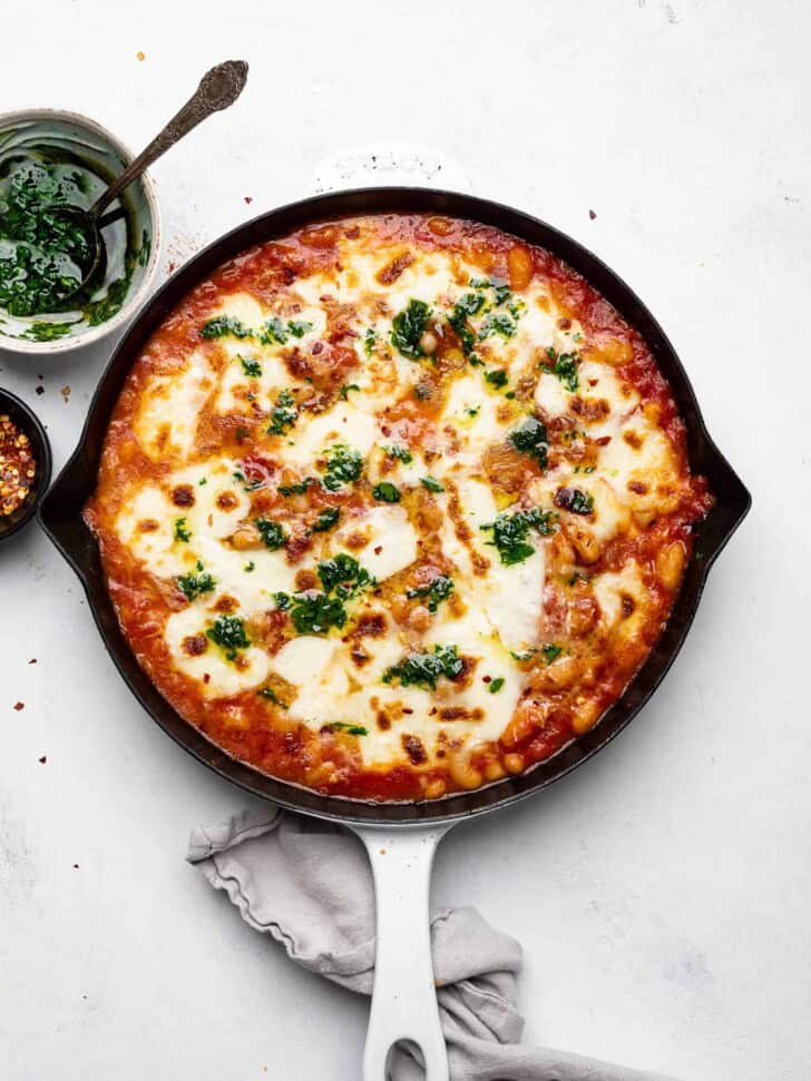 cheesy baked beans with tomatoes drizzled with parsley oil