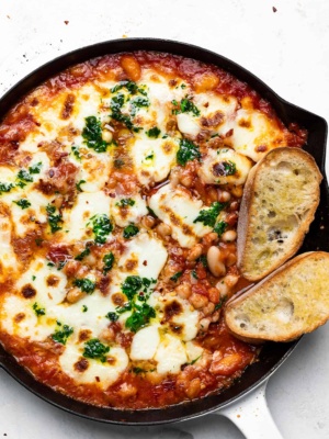 Cheesy Baked Beans with tomatoes in skillet with crusty bread