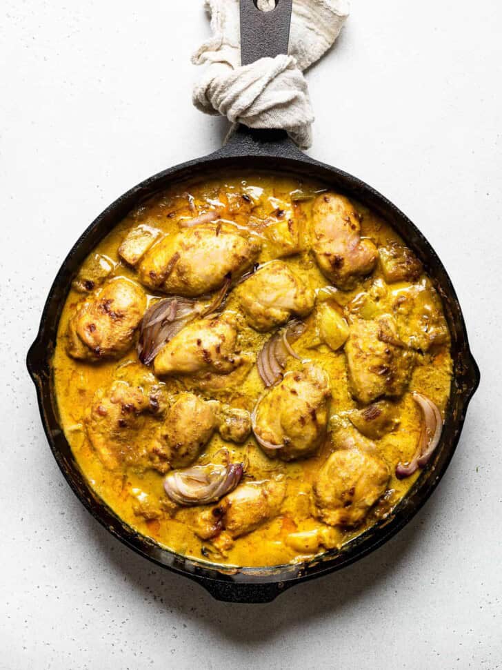 cooked chicken thighs with curry sauce in skillet 