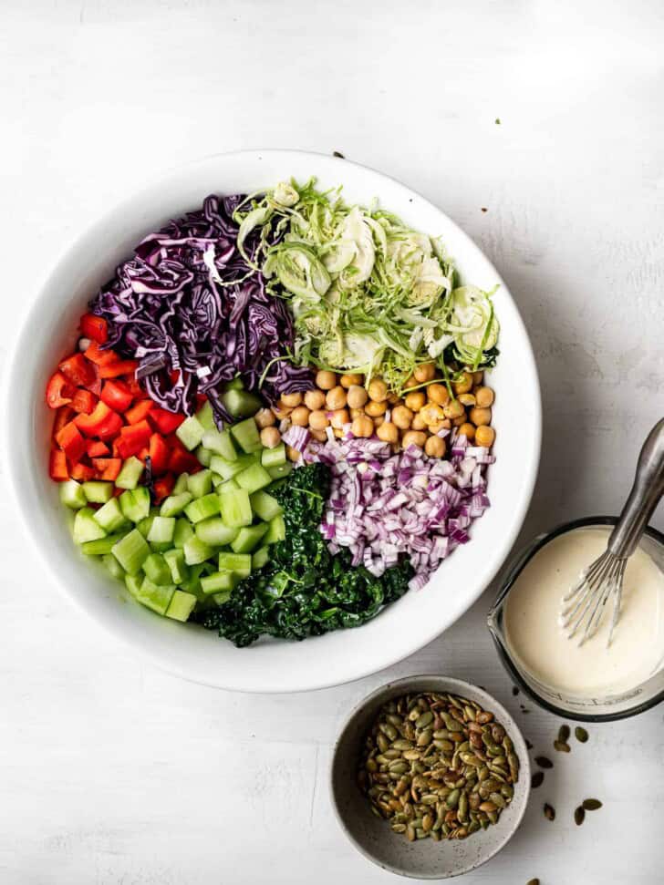 salad ingredients in bowl with dressing and pepitas on the side