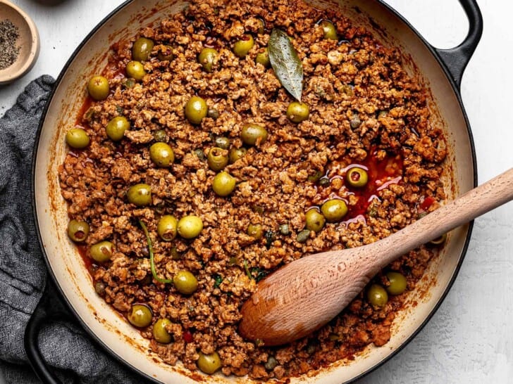 The finished dish of turkey picadillo in saucepan with wooden spoon. 