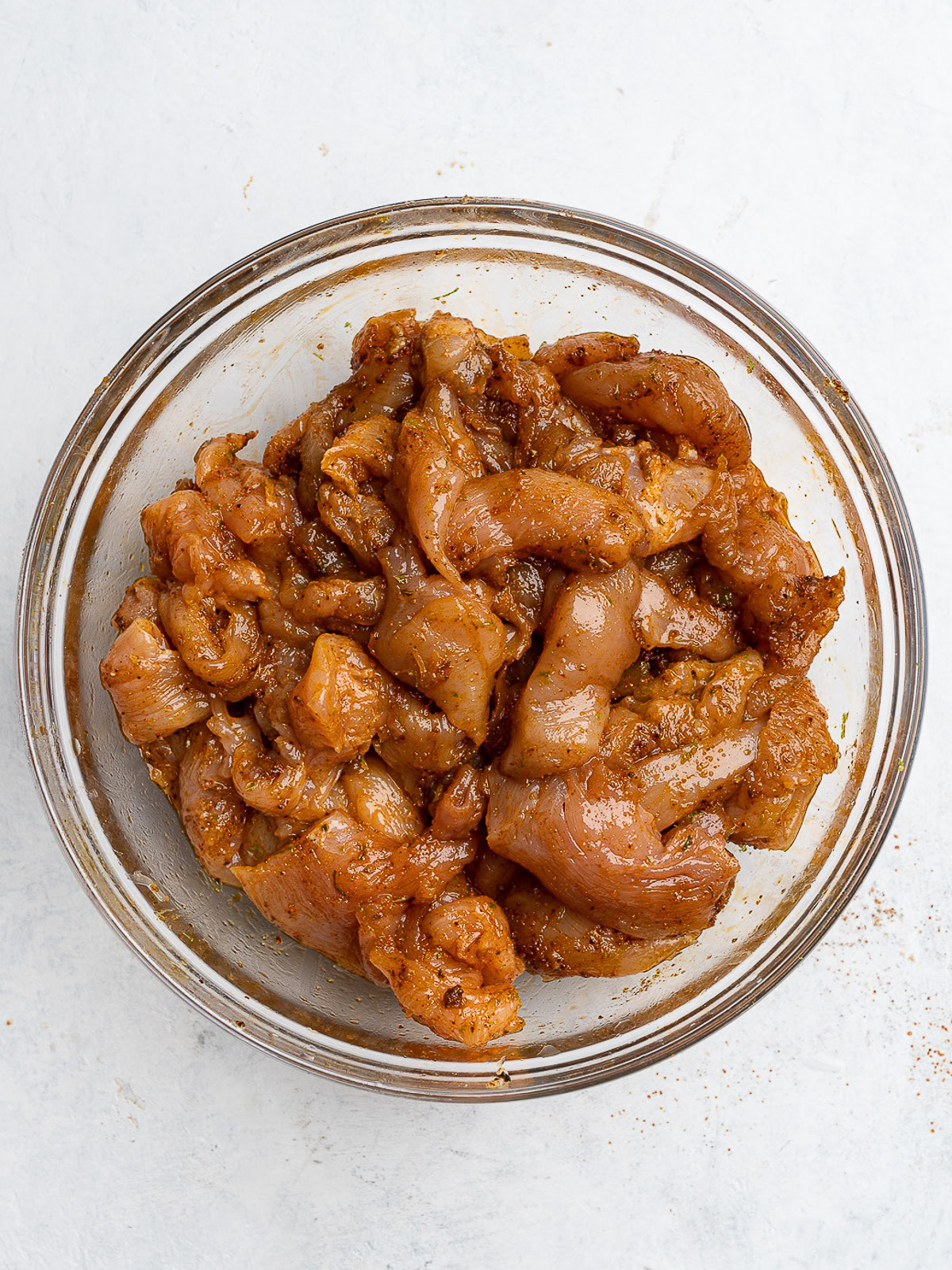 chicken pieces marinating in glass bowl