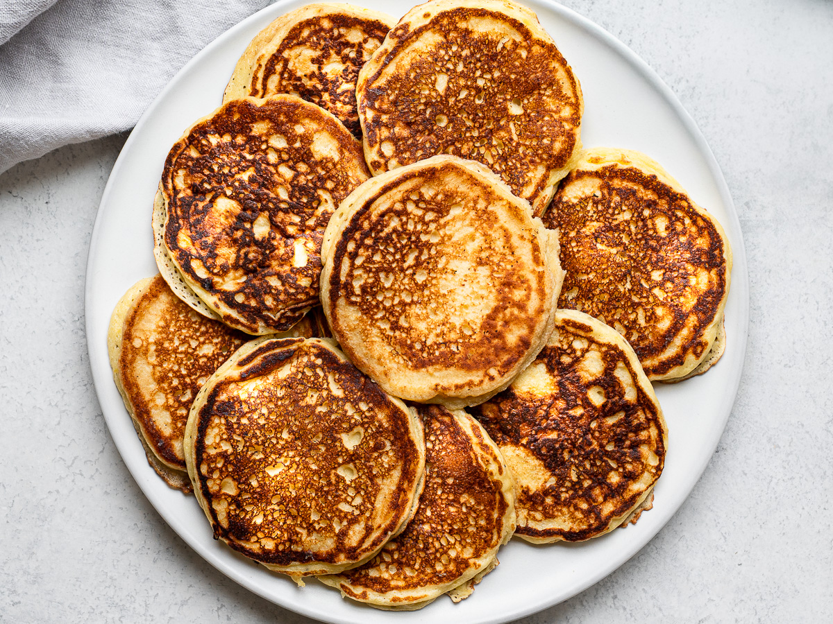 Cooked pancakes on white platter.