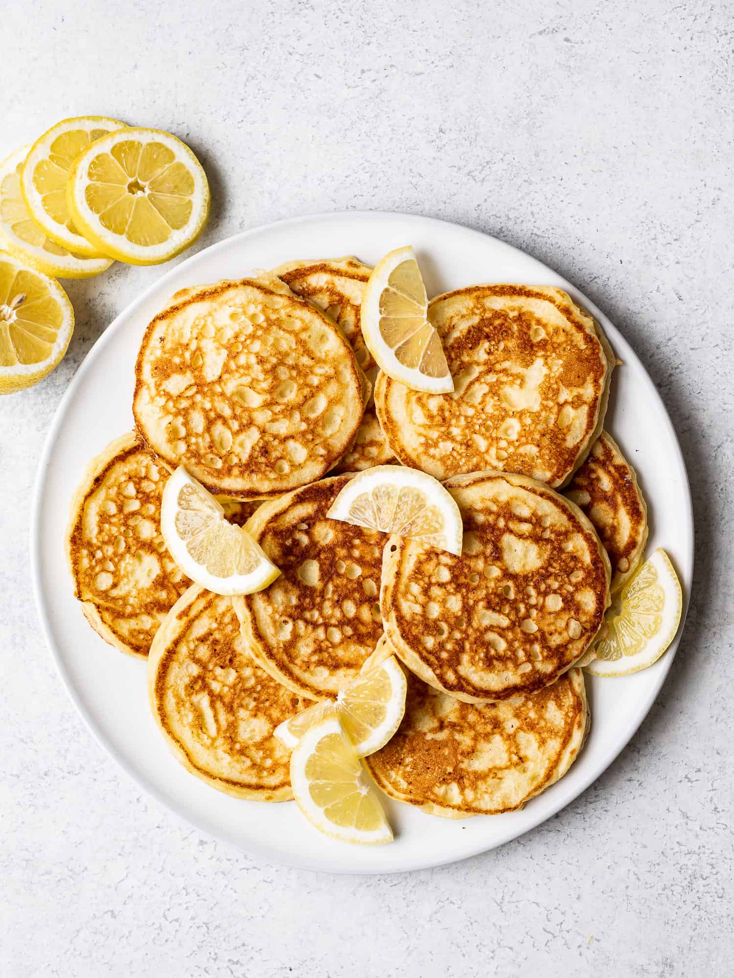 lemon ricotta pancakes on plate with slices of lemon