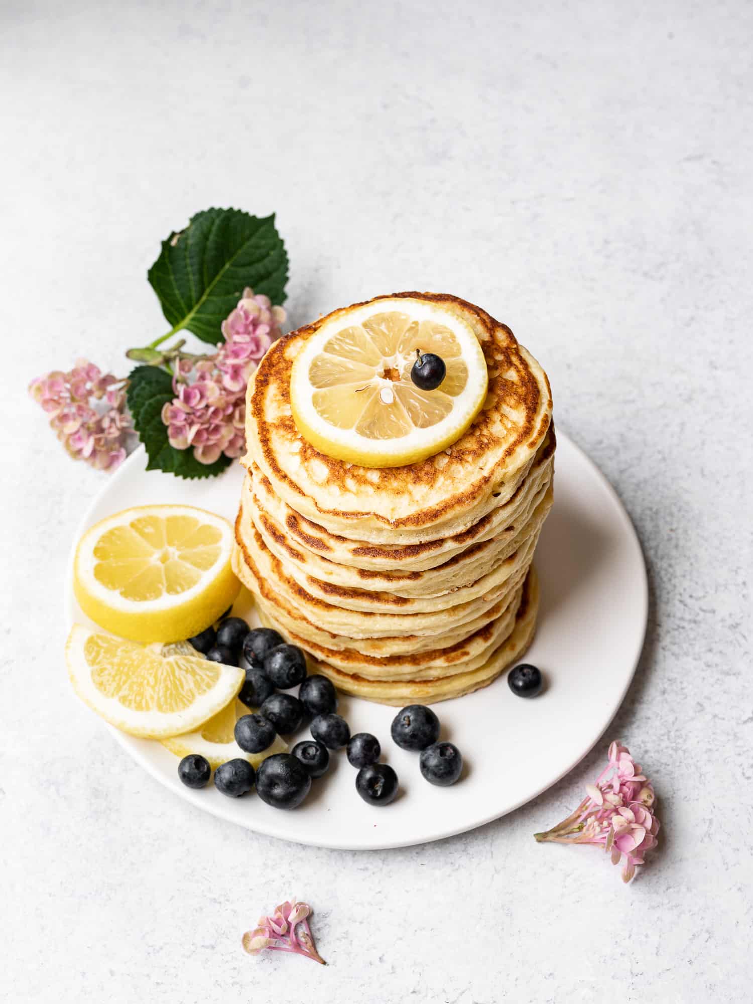 lemon ricotta pancakes stacked on a plate with blueberries