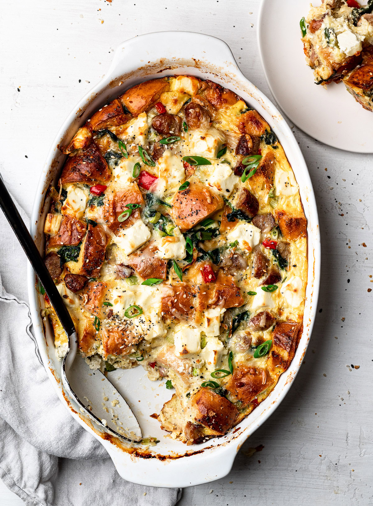 a piece of baked casserole missing from baking dish with a served piece on the side