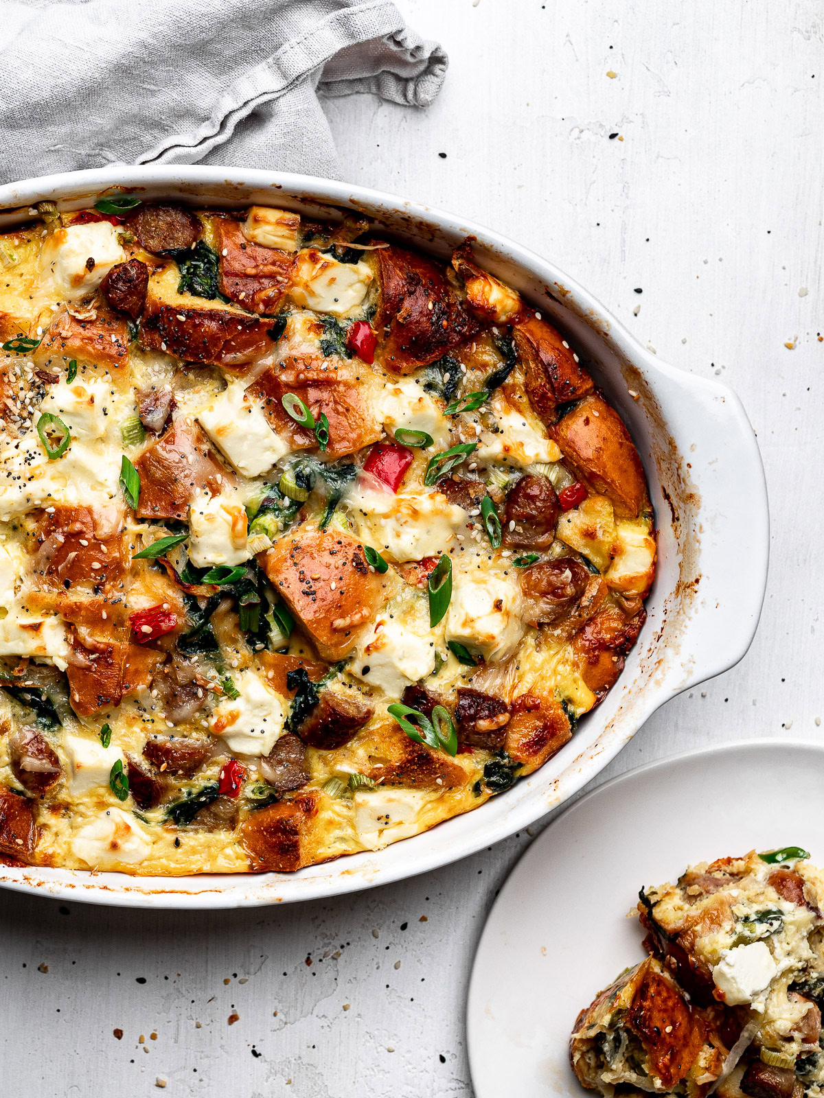 close up of baked casserole in baking dish with a served piece on the side