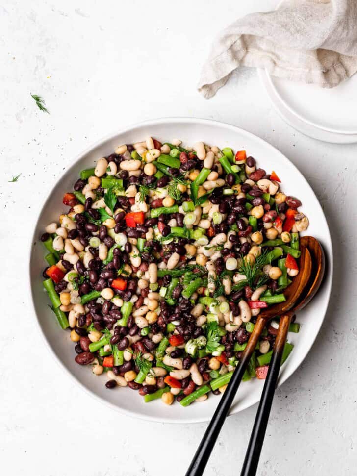 5 bean salad served in bowl with salad plates on the side