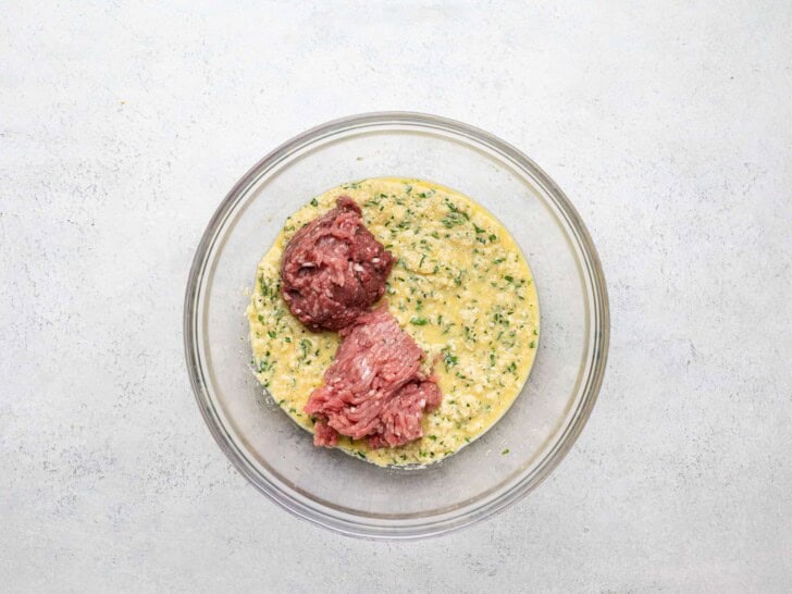 Adding ground beef and ground pork to bread crumb mixture