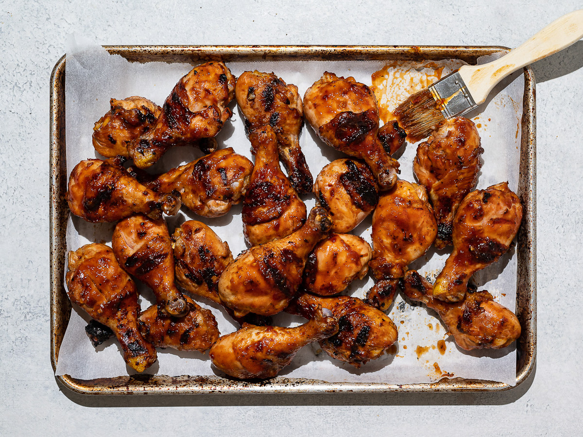 Grilled drumsticks on sheet pan with glazing brush. 