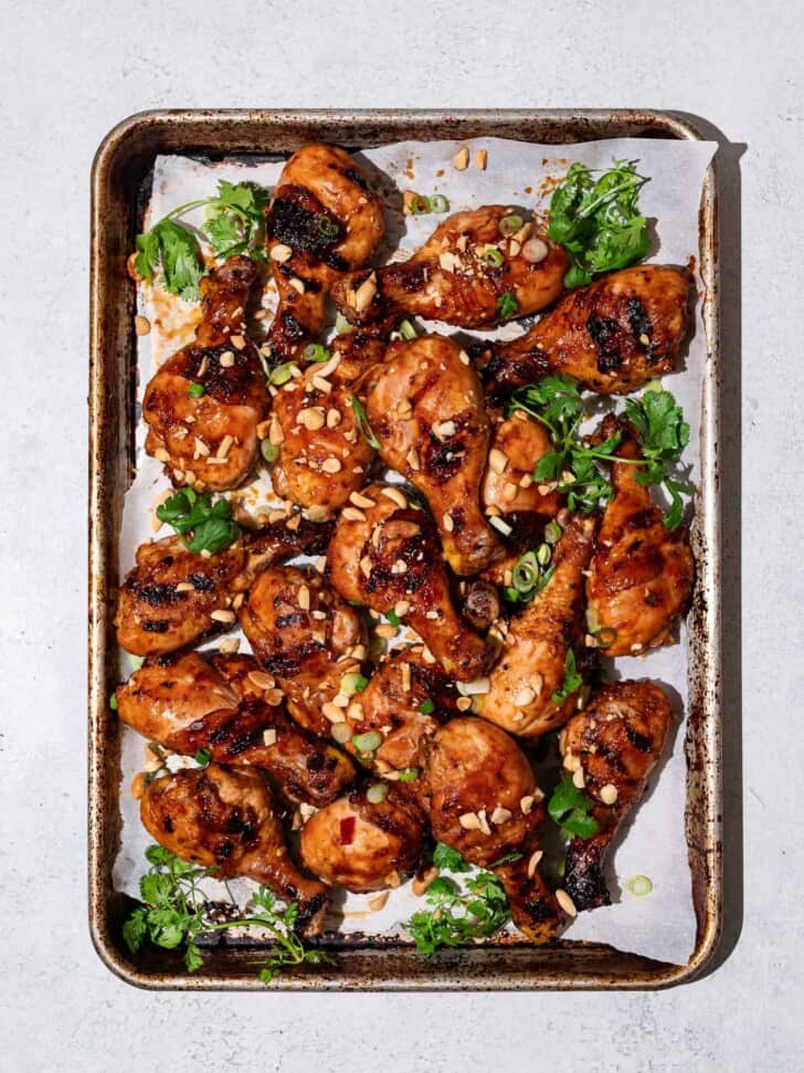 Sweet and sticky grilled drumsticks on sheet pan with crushed peanuts