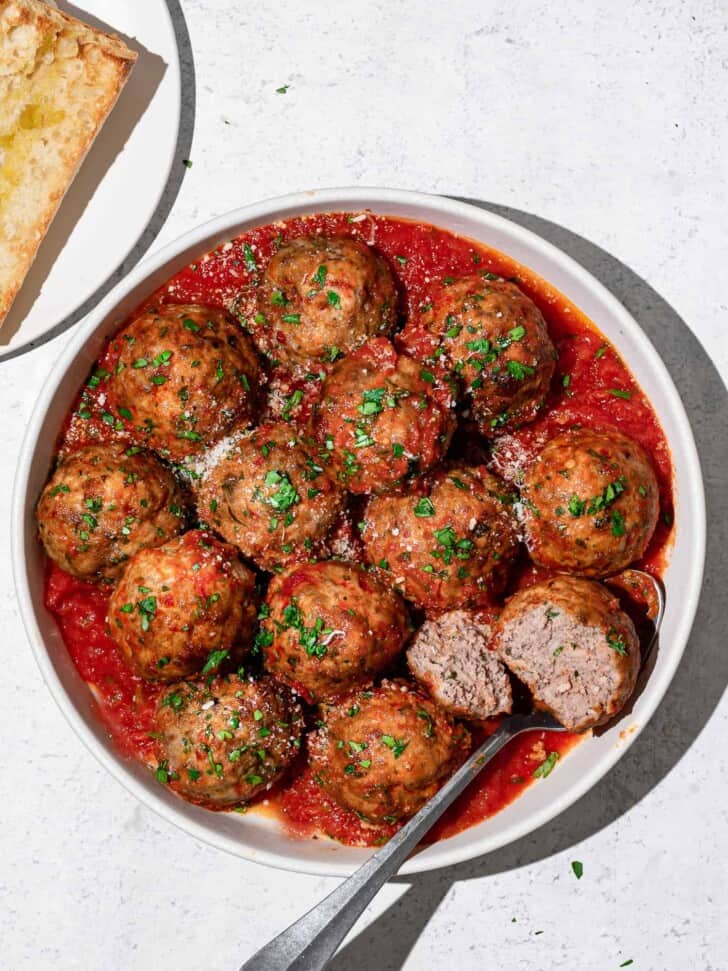 Italian meatballs with tomato sauce on plate with bread on the side