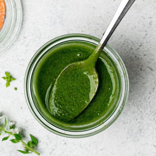 top view of basil vinaigrette in jar with spoon