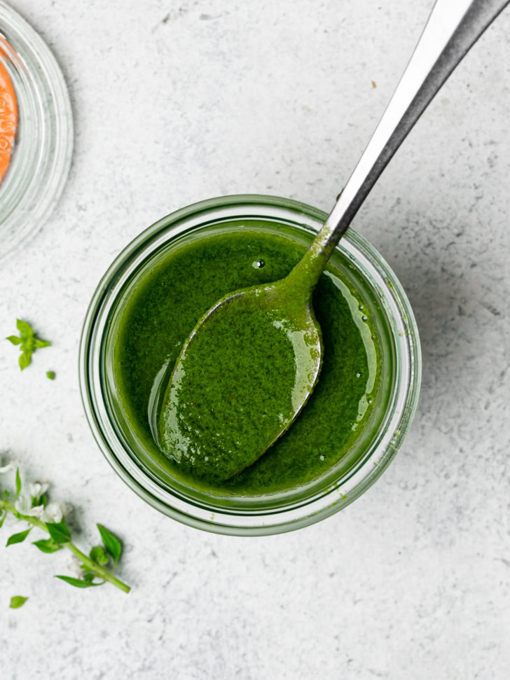 top view of basil vinaigrette in jar with spoon