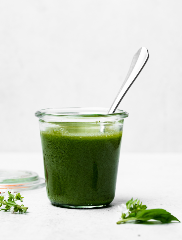 side view of basil vinaigrette in jar with spoon