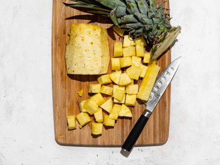 Cutting pineapple chunks on cutting board