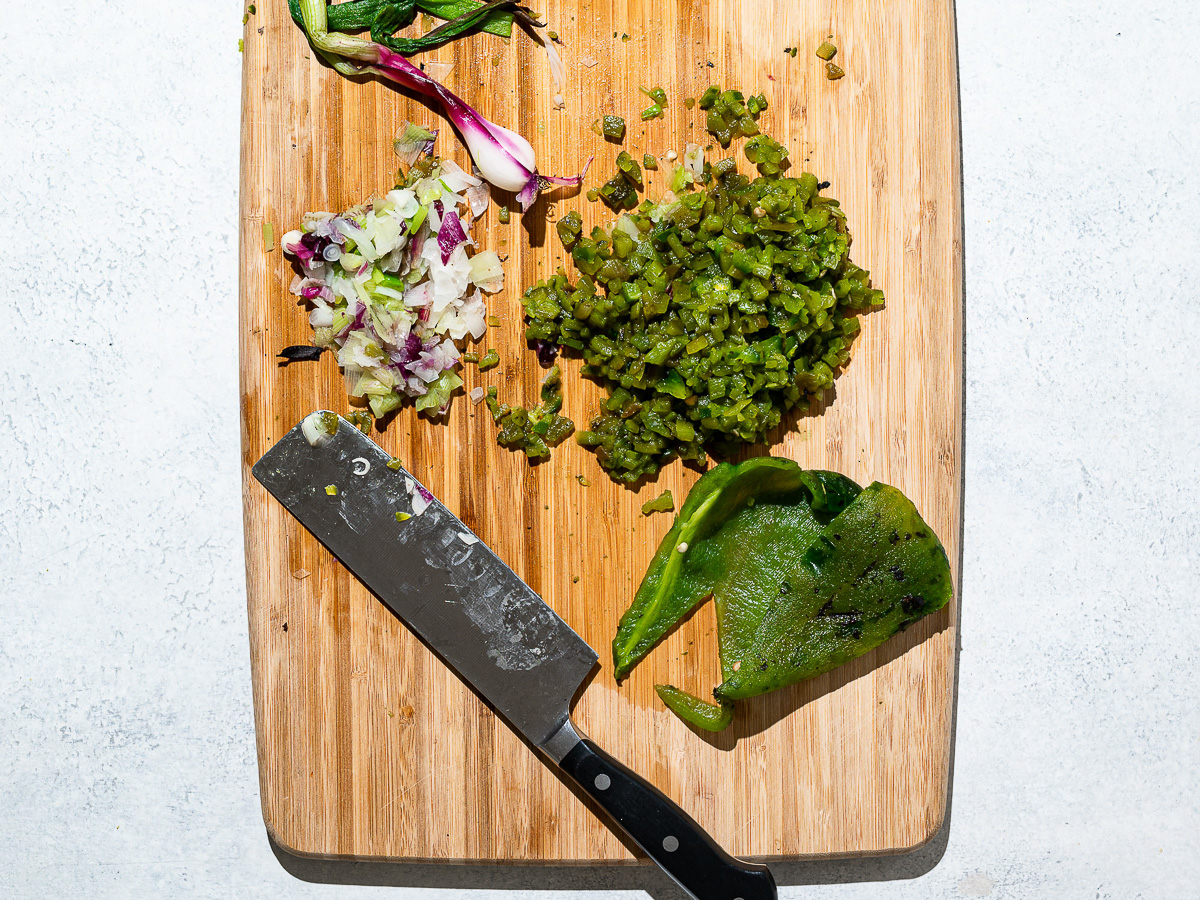 Finely diced roasted poblano peppers on wood cutting board.