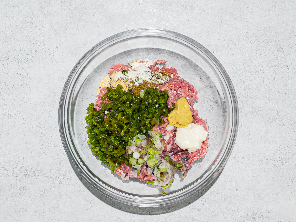 Burger mixture in glass mixing bowl.