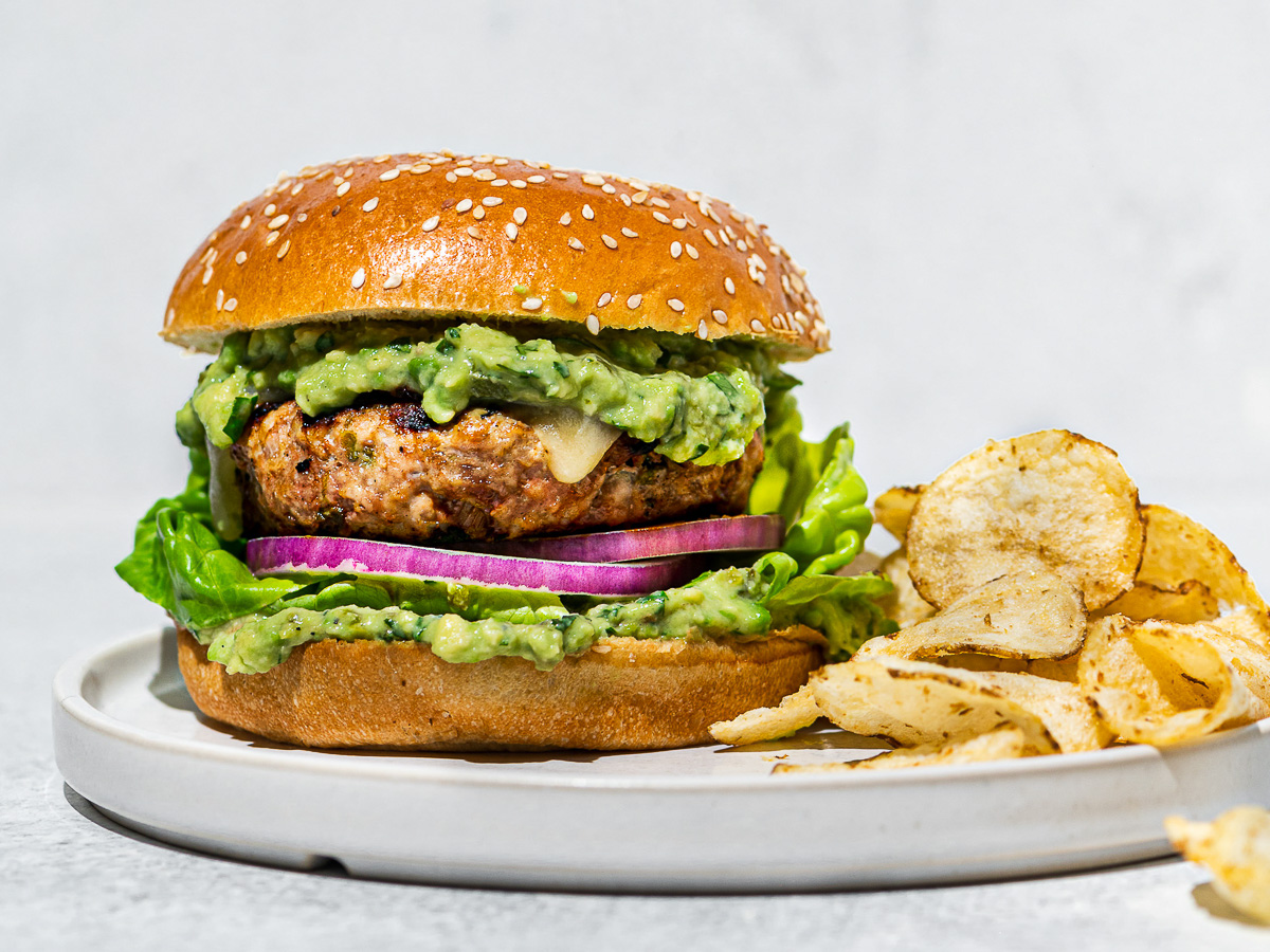 Close-up of poblano Turkey burger on white plate with chips.