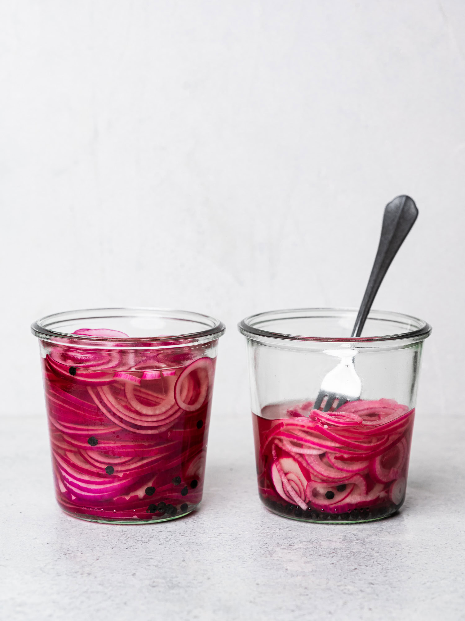 side-view of two jars of pickled red onions