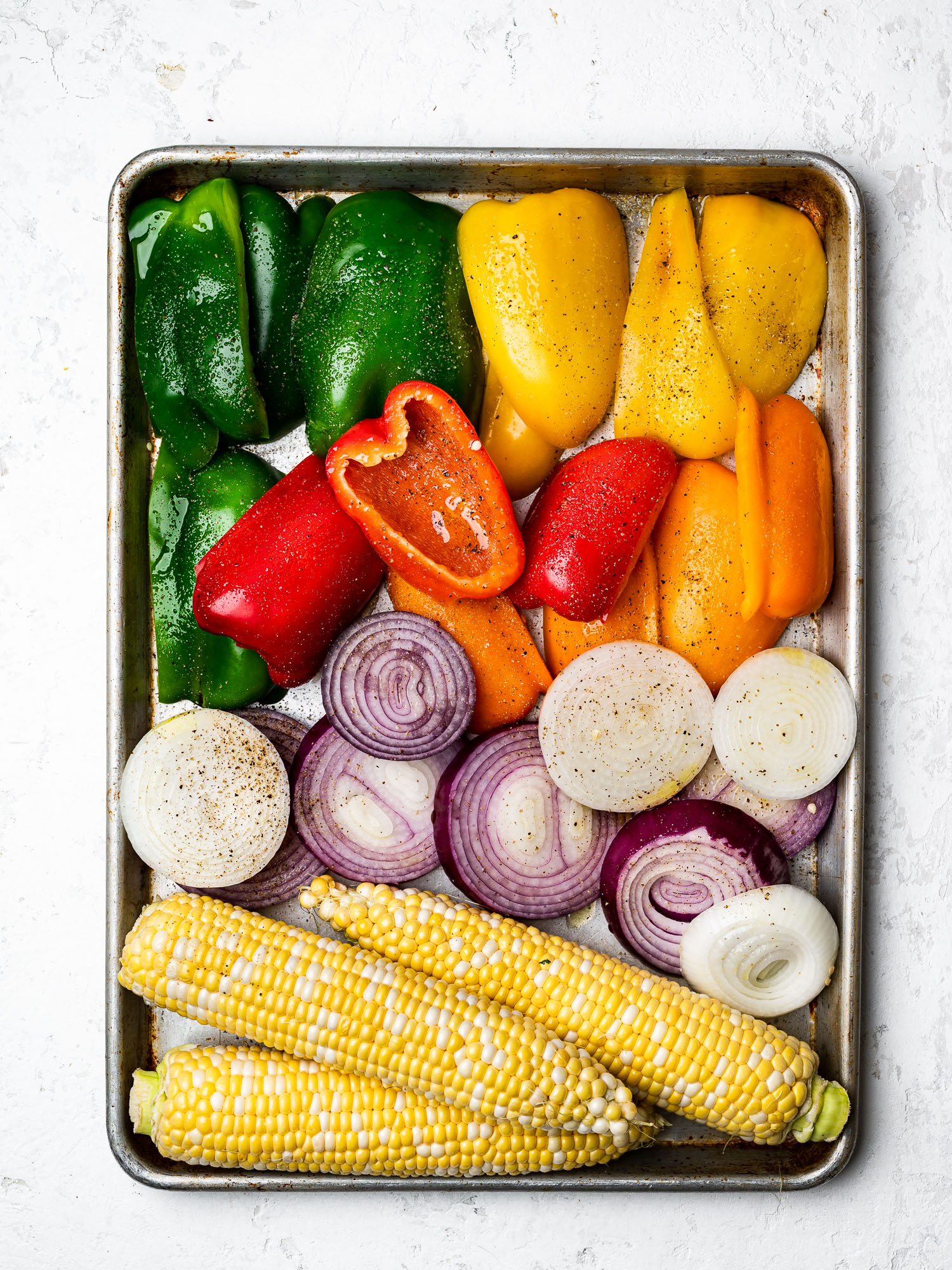 cut peppers, onions and corn on a sheet pan
