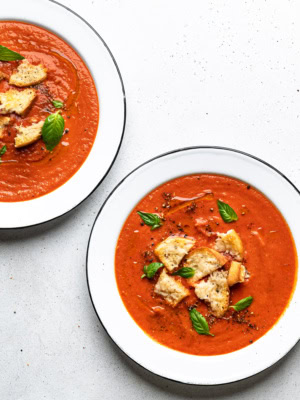 roasted tomato soup served in bowls and topped with parmesan toasts