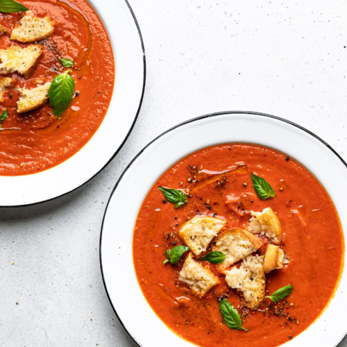 roasted tomato soup served in bowls and topped with parmesan toasts