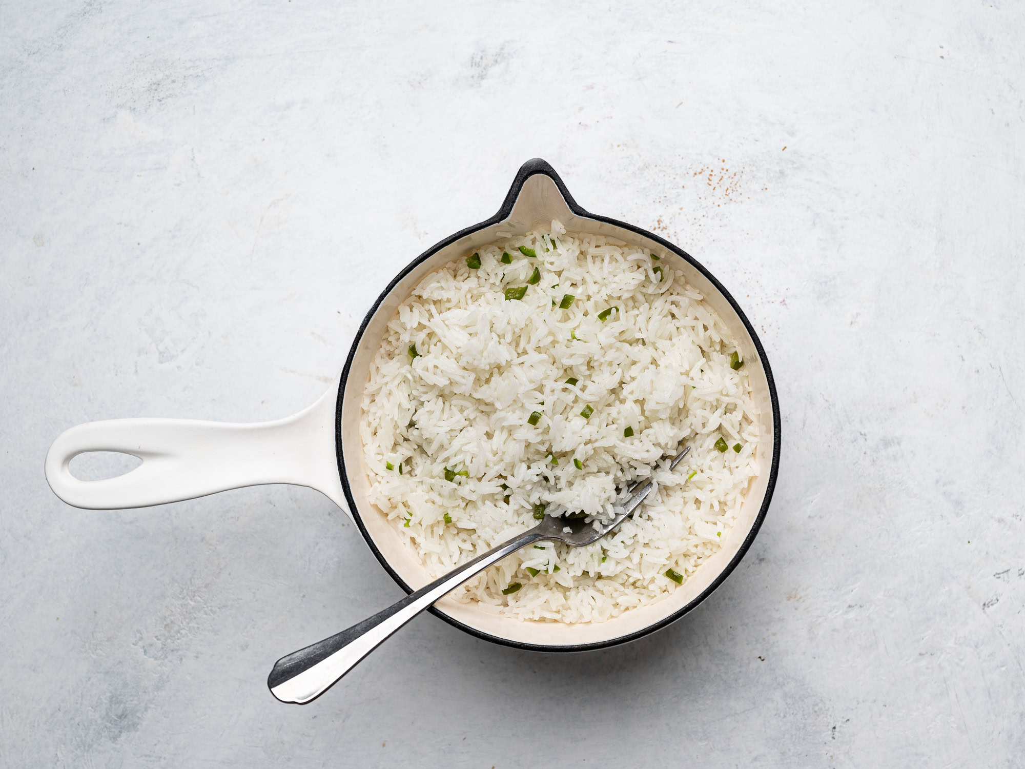 fluffing cooked rice in pot with a fork