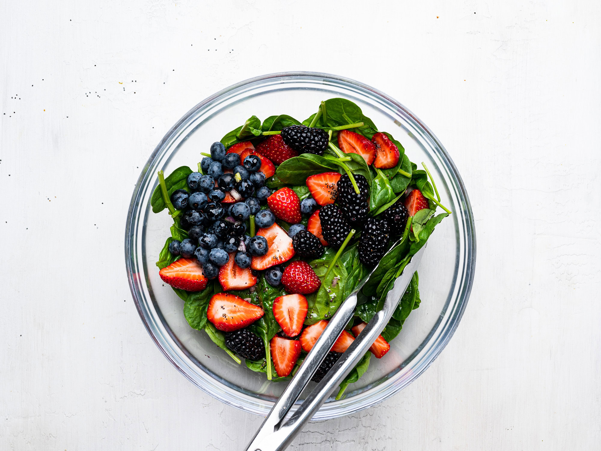 mixing the berries with spinach in bowl