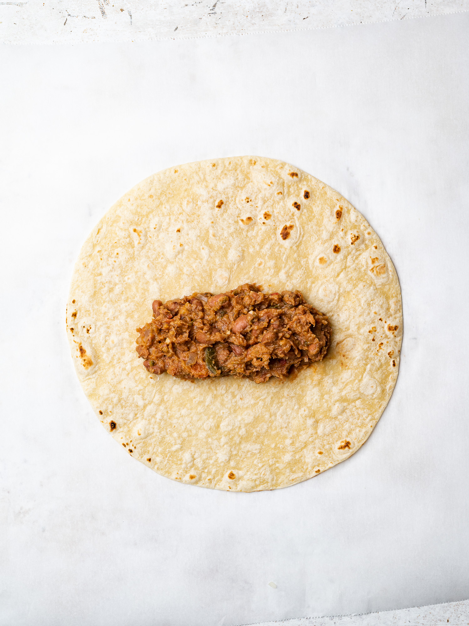 spreading refried beans on tortilla