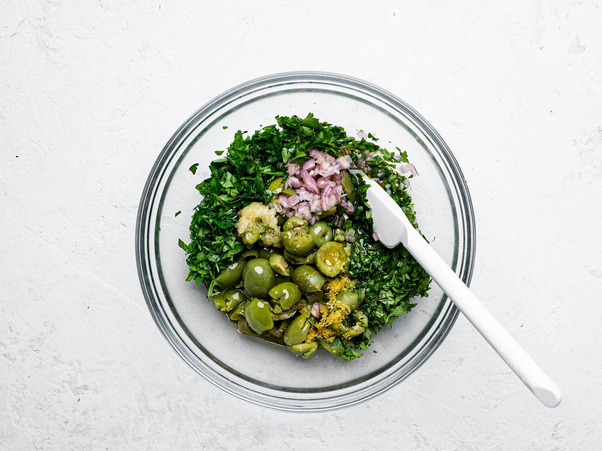 mixing green olive salsa in glass bowl