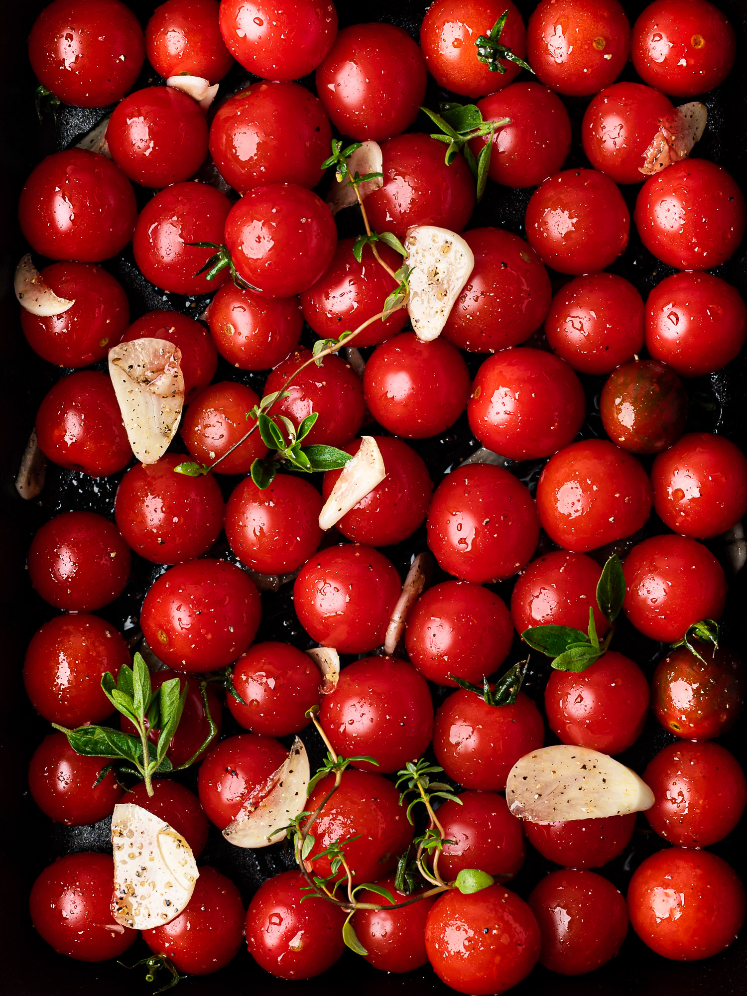 raw cherry tomatoes in baking dish with garlic and herbs