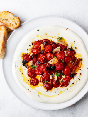 whipped feta with roasted cherry tomatoes on platter with toasted baguette