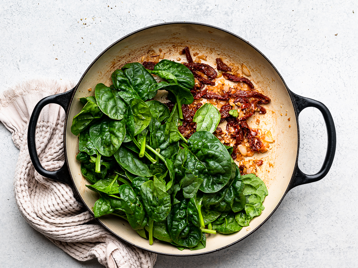 adding spinach to the skillet