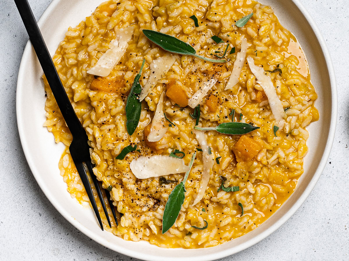 butternut squash risotto served on plate topped with fresh sage leaves