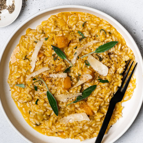 butternut squash risotto served on plate topped with fresh sage leaves
