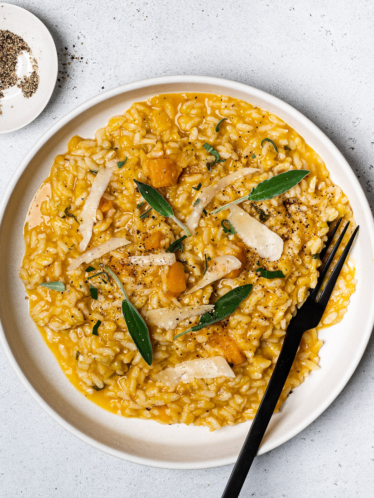 butternut squash risotto served on plate topped with fresh sage leaves