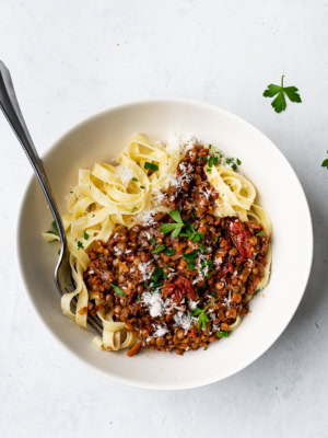 Lentil bolognese served over pasta in bowl