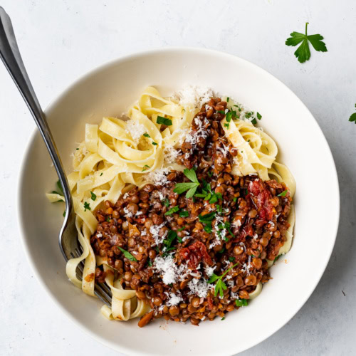 Lentil bolognese served over pasta in bowl